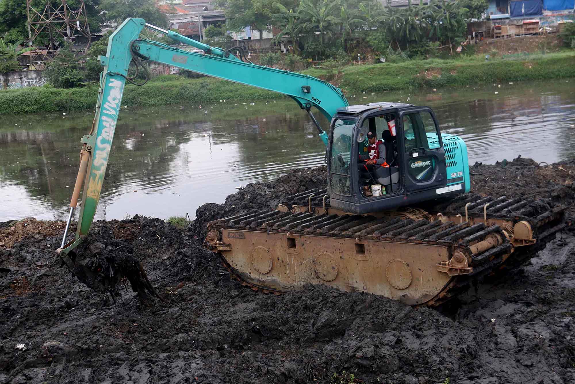 Petugas mengoperasikan alat berat untuk mengeruk lumpur di Sungai Ciliwung, Jakarta, Jumat, (30/8/2024).  (BeritaNasional.com/ Oke Atmaja)