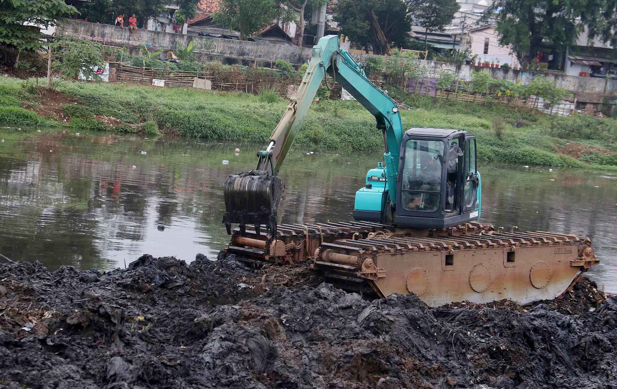 Petugas mengoperasikan alat berat untuk mengeruk lumpur di Sungai Ciliwung, Jakarta, Jumat, (30/8/2024).  (BeritaNasional.com/ Oke Atmaja)