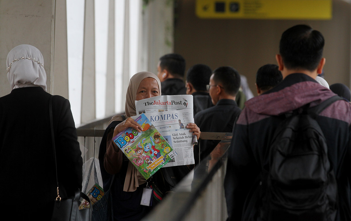 Seorang penjual koran menawarkan daganganya saat berjualan di Jembatan Penyebrangan Orang Halte Transjakarta Jenderal Sudirman, Jakarta, Rabu (08/01/2025).(BeritaNasional.com/Oke Atmaja)