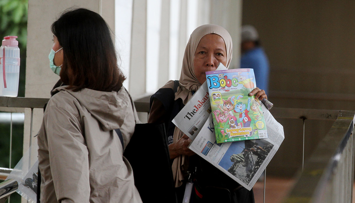 Seorang penjual koran menawarkan daganganya saat berjualan di Jembatan Penyebrangan Orang Halte Transjakarta Jenderal Sudirman, Jakarta, Rabu (08/01/2025).(BeritaNasional.com/Oke Atmaja)