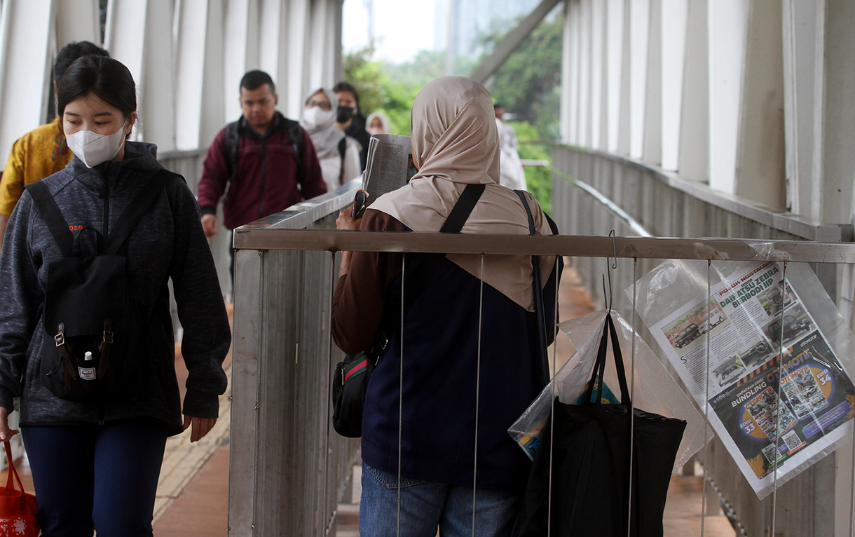 Seorang penjual koran menawarkan daganganya saat berjualan di Jembatan Penyebrangan Orang Halte Transjakarta Jenderal Sudirman, Jakarta, Rabu (08/01/2025).(BeritaNasional.com/Oke Atmaja)