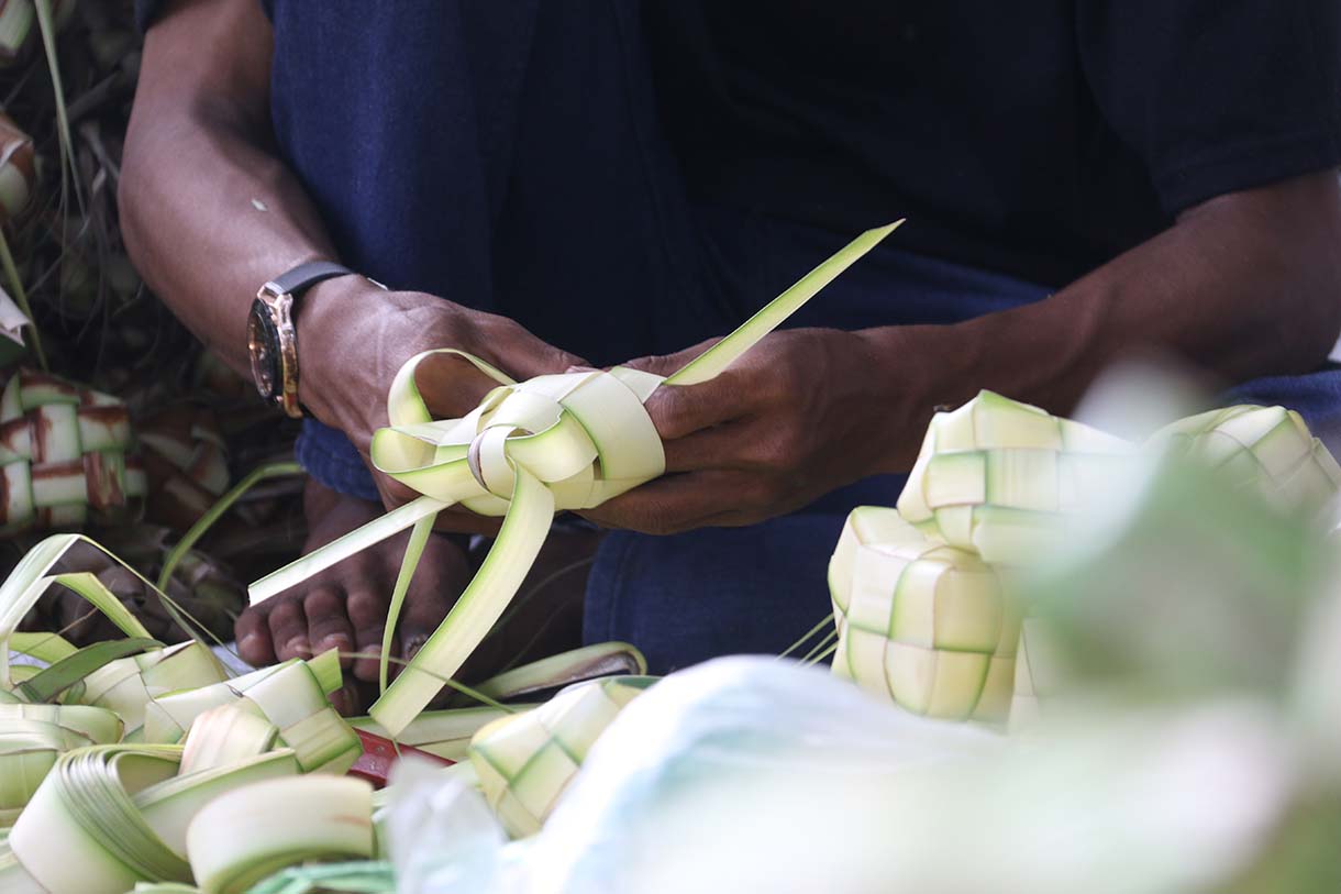 Pedagang menganyam kulit ketupat di Pasar Pondok Labu, Jakarta, Jumat (20/3/2026).(Beritanasional.com/Oke Atmaja)