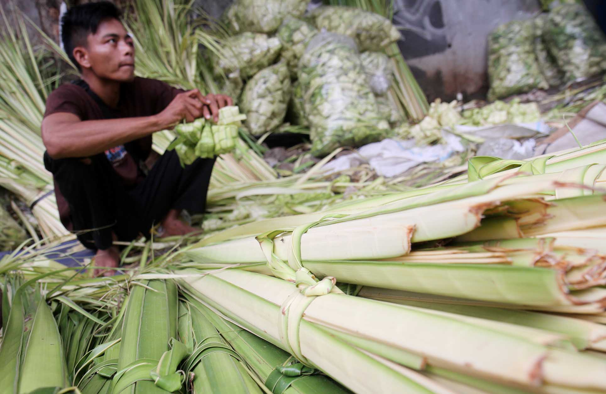 Pedagang membuat bungkus ketupat di Pasar Minggu, Jakarta, Jumat (5/4/2024).  (BeritaNasional.com/Oke Atmaja)