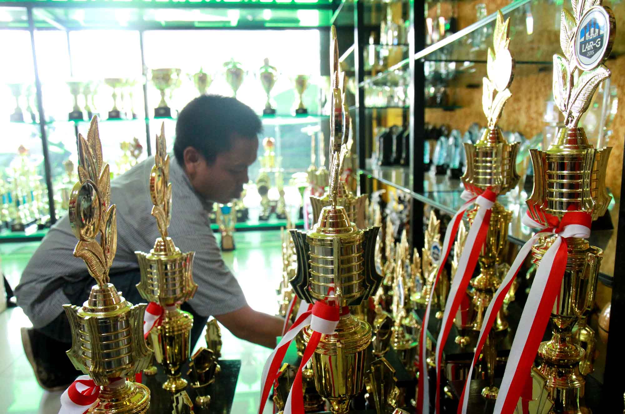 Pengrajin menyelesaikan proses pembuatan piala di tokonya di kawasan Senen, Jakarta, Selasa (6/8/2024) (BeritaNasional.com/Oke Atmaja)