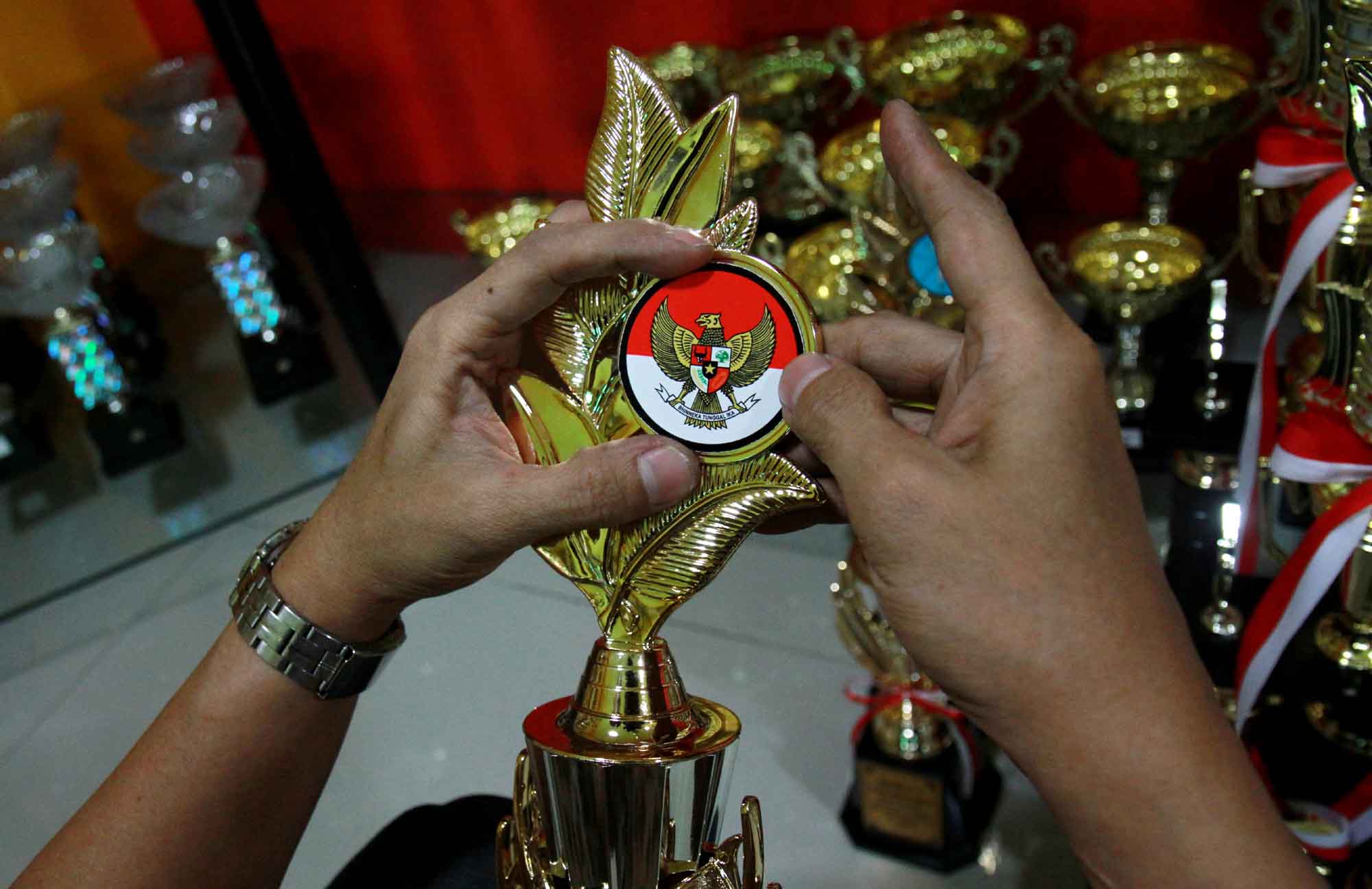 Pengrajin menyelesaikan proses pembuatan piala di tokonya di kawasan Senen, Jakarta, Selasa (6/8/2024) (BeritaNasional.com/Oke Atmaja)