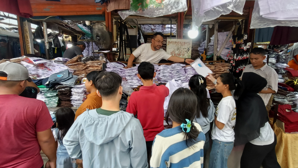 Pedagang melayani calon pembeli seragam sekolah di Pasar Jatinegara, Jakarta, Minggu (12/7/2026). (Beritanasional.com/Oke Atmaja)