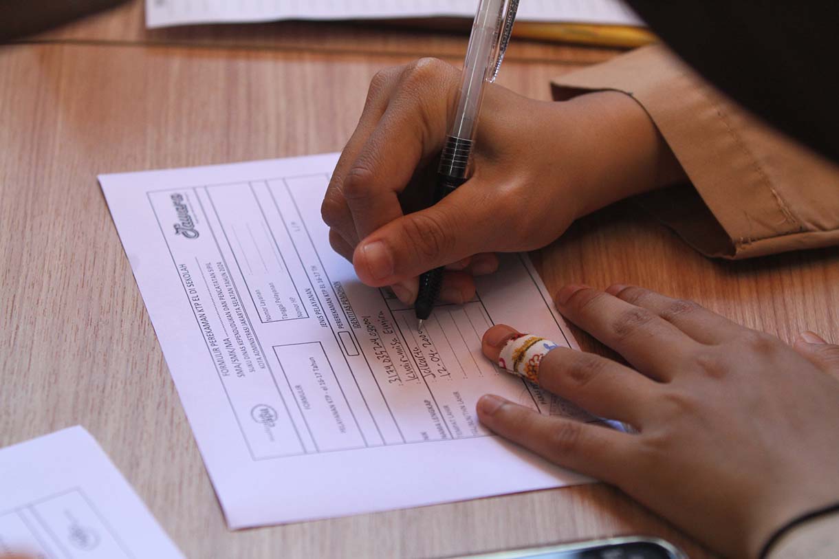 Petugas Suku Dinas Kependudukan dan Catatan Sipil (Sudin Dukcapil) Jakarta Selatan mengarahkan pelajar saat perekaman data KTP elektronik di Madrasah Aliyah Al-Khairiyah, Mampang Prapatan, Jakarta, Rabu (28/8/2025).  (Beritanasional.com/Oke Atmaja)
