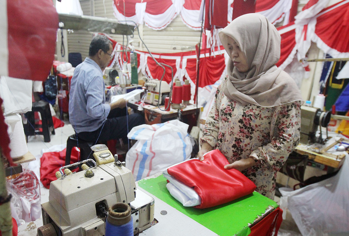 Pekerja menjahit bendera dan rempel di tempat konveksi dan toko di Blok 3 Pasar Senen, Jakarta, Jumat (2/8/2024). (BeritaNasional.com/Oke Atmaja)