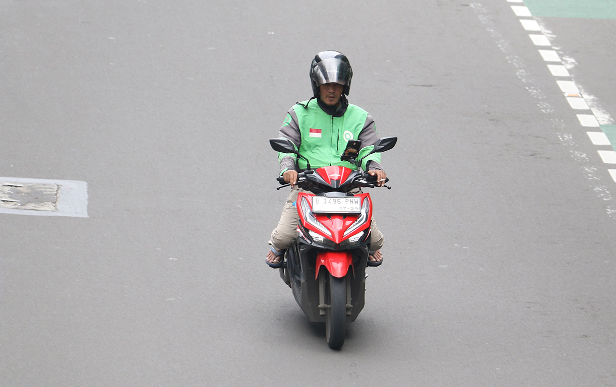 Pengemudi ojek online membawa penumpang melintas di Jalan Rasuna Sahid, Jakarta, Selasa (27/1/2026).  (Beritanasional.com/Oke Atmaja)