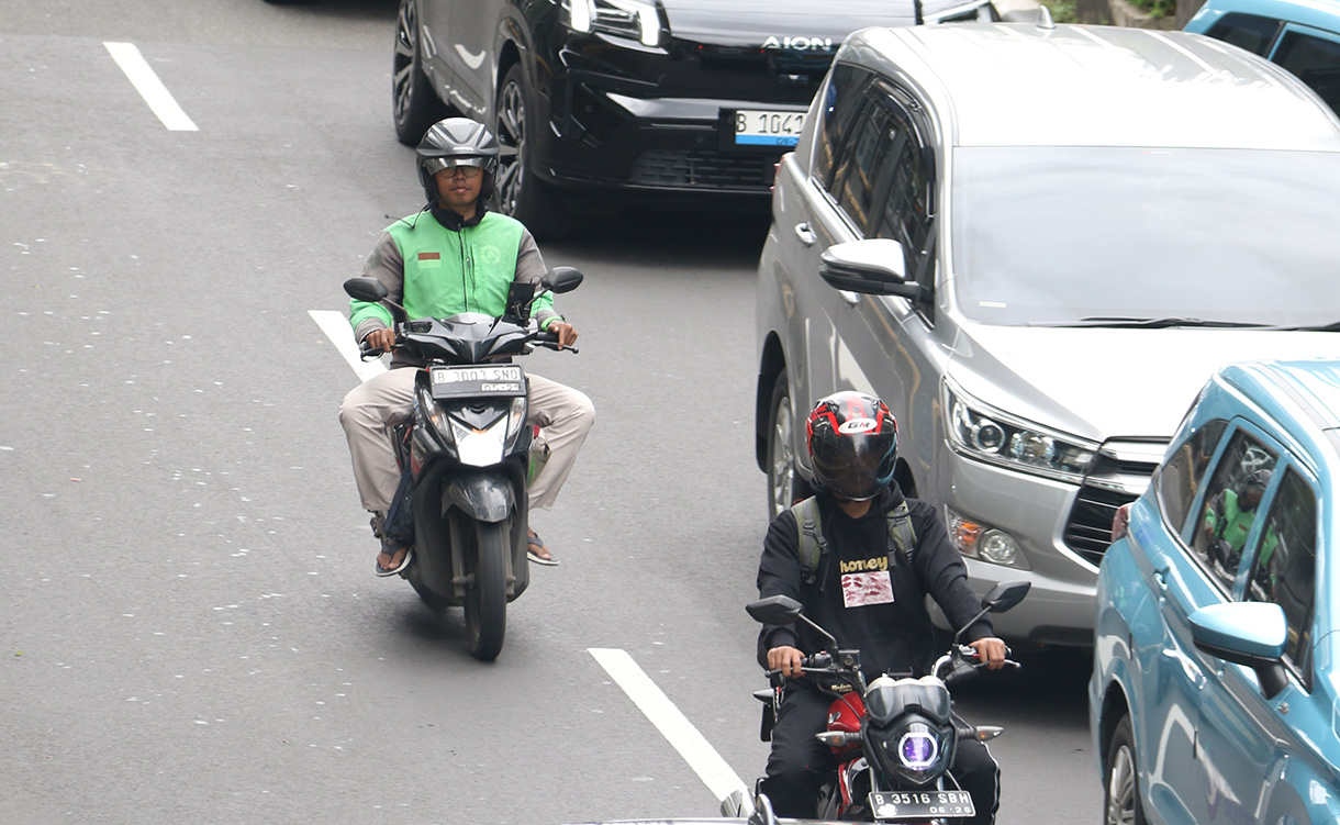 Pengemudi ojek online membawa penumpang melintas di Jalan Rasuna Sahid, Jakarta, Selasa (27/1/2026).  (Beritanasional.com/Oke Atmaja)