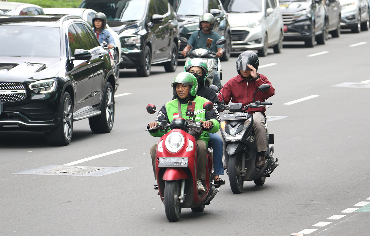 Pengemudi ojek online membawa penumpang melintas di Jalan Rasuna Sahid, Jakarta, Selasa (27/1/2026).  (Beritanasional.com/Oke Atmaja)