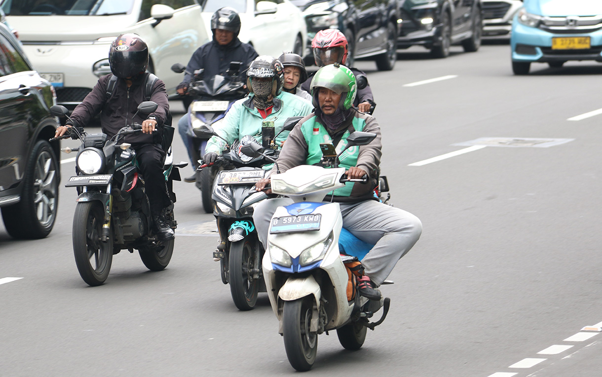 Pengemudi ojek online membawa penumpang melintas di Jalan Rasuna Sahid, Jakarta, Selasa (27/1/2026).  (Beritanasional.com/Oke Atmaja)