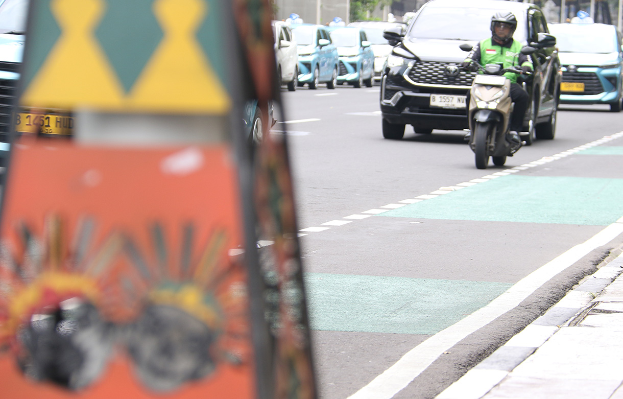 Pengemudi ojek online membawa penumpang melintas di Jalan Rasuna Sahid, Jakarta, Selasa (27/1/2026).  (Beritanasional.com/Oke Atmaja)