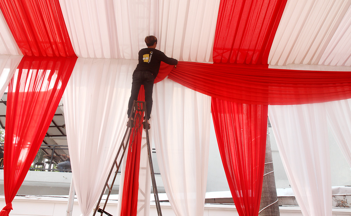 Pekerja memasang tirai di tiang tenda di kantor KPUD DKI Jakarta,Sabtu (24/8/2024).  (BeritaNasional.com/ Oke Atmaja)