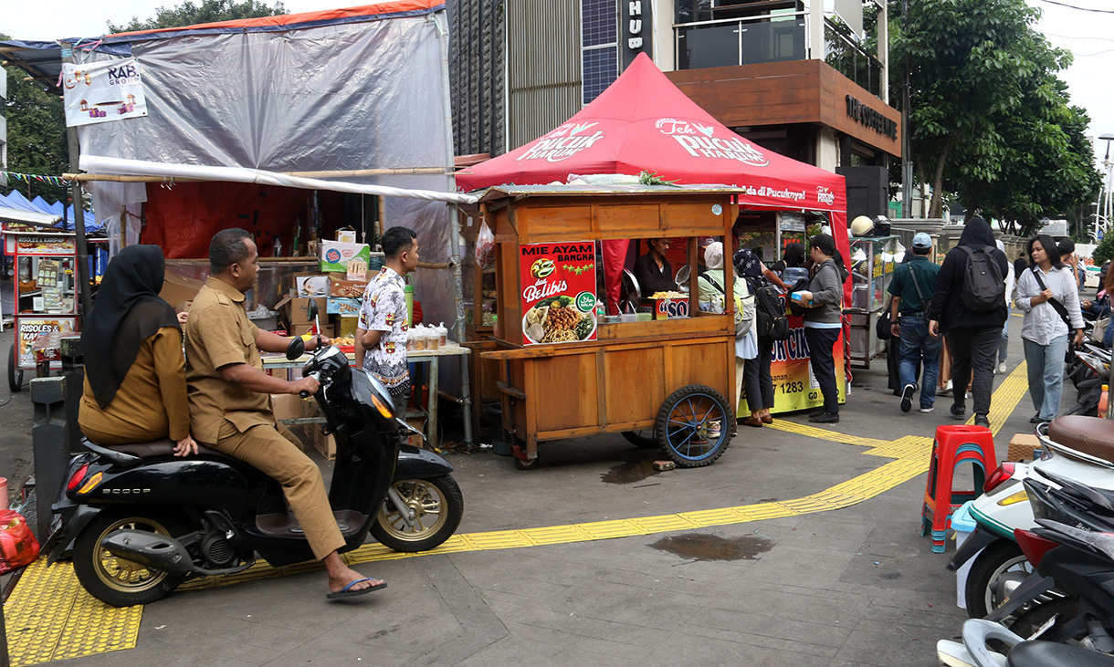 Warga berjalan ditengah lapak pedagang kaki lima (PKL) di trotoar Cikini, Jakarta, Senin (23/2/2026). (Beritanasional.com/Oke Atmaja)