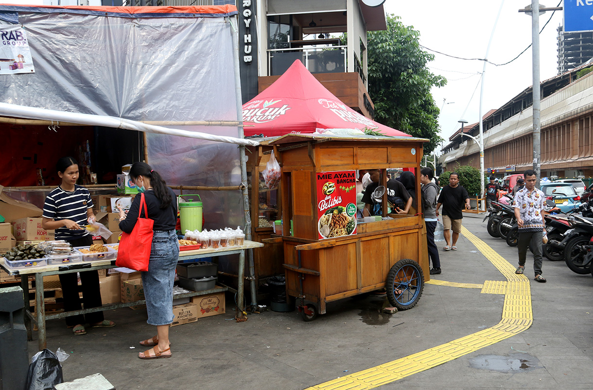 Warga berjalan ditengah lapak pedagang kaki lima (PKL) di trotoar Cikini, Jakarta, Senin (23/2/2026). (Beritanasional.com/Oke Atmaja)