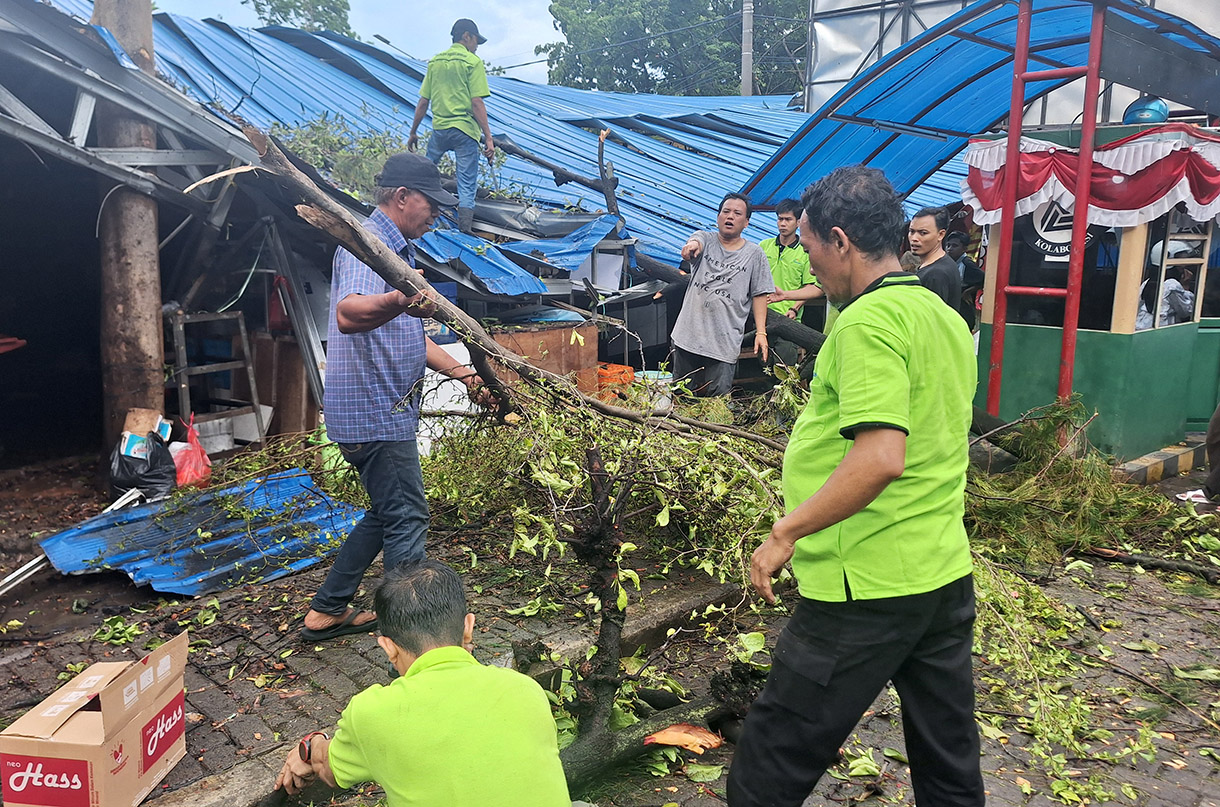 Petugas dibantu pedagang mengevakuasi sebatang pohon yang tumbang di Pasar Senin, Jakarta, Senin (02/12/2024). (BeritaNasional.com/Oke Atmaja)