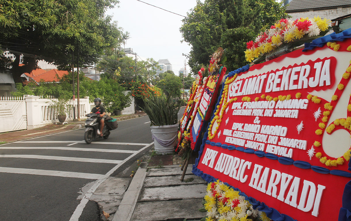 Warga melintasi karang bunga yang berjejer di sekitar Rumah Pemenangan pasangan cagub dan cawagub DKI Jakarta Pramono Anung dan Rano Karno di Jalan Cemara, Jakarta, Minggu(01/12/2024). (BeritaNasional.com/Oke Atmaja)