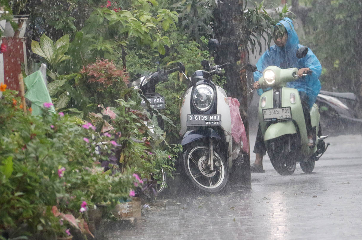 Warga menggunakan payung menerobos hujan di Jalan Menteng Jaya, Jakarta, Selasa (18/11/2025). (Beritanasional.com/Oke Atmaja)