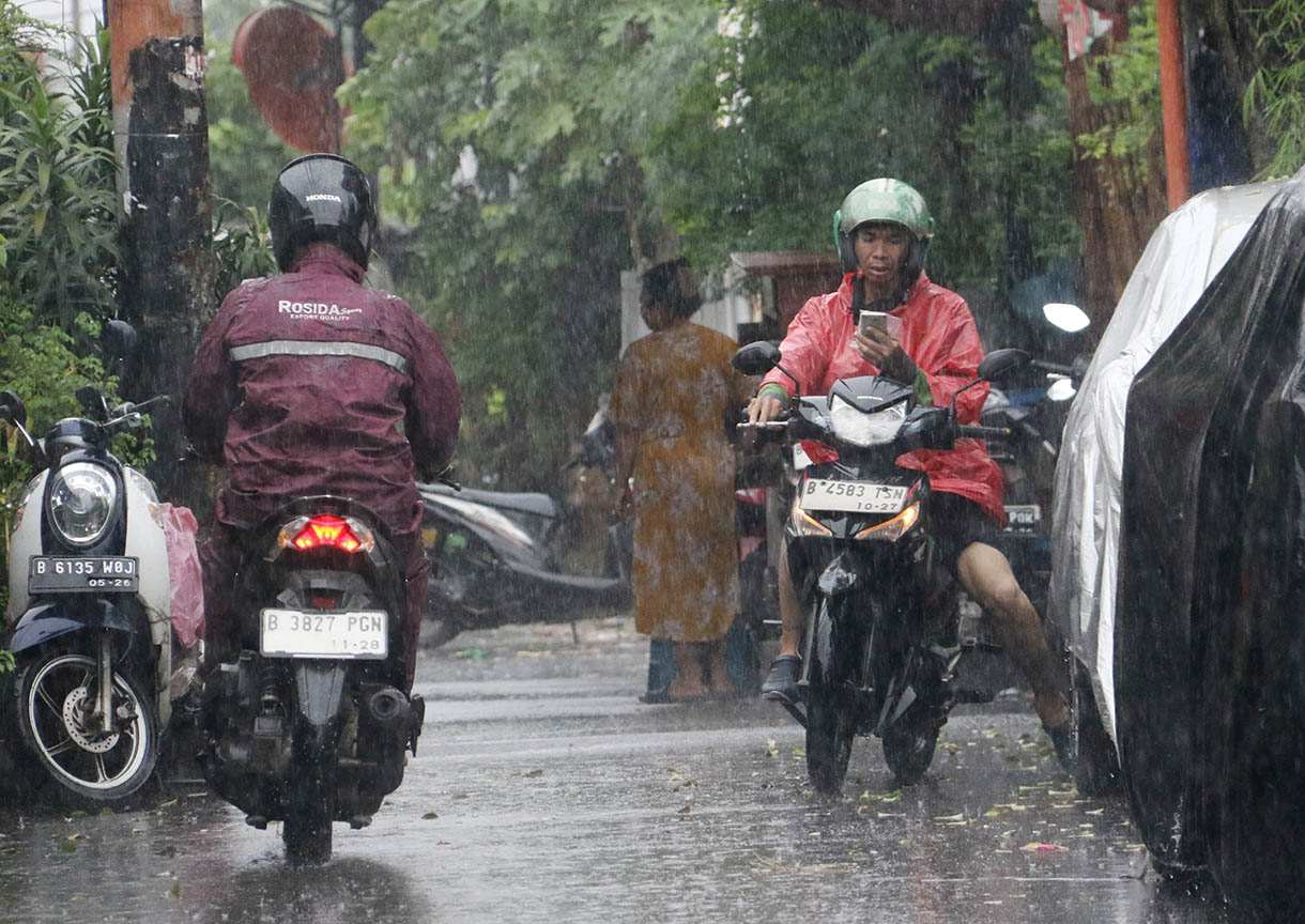 Warga menggunakan payung menerobos hujan di Jalan Menteng Jaya, Jakarta, Selasa (18/11/2025). (Beritanasional.com/Oke Atmaja)