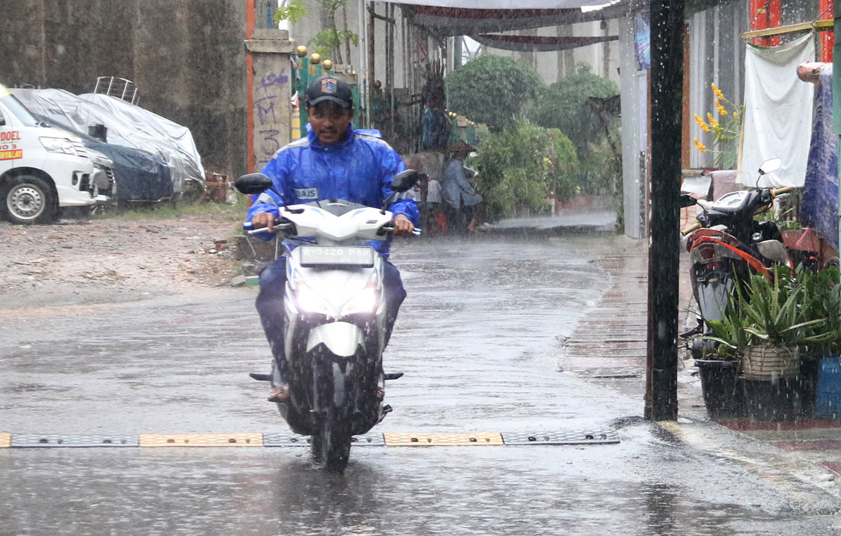 Warga menggunakan payung menerobos hujan di Jalan Menteng Jaya, Jakarta, Selasa (18/11/2025). (Beritanasional.com/Oke Atmaja)
