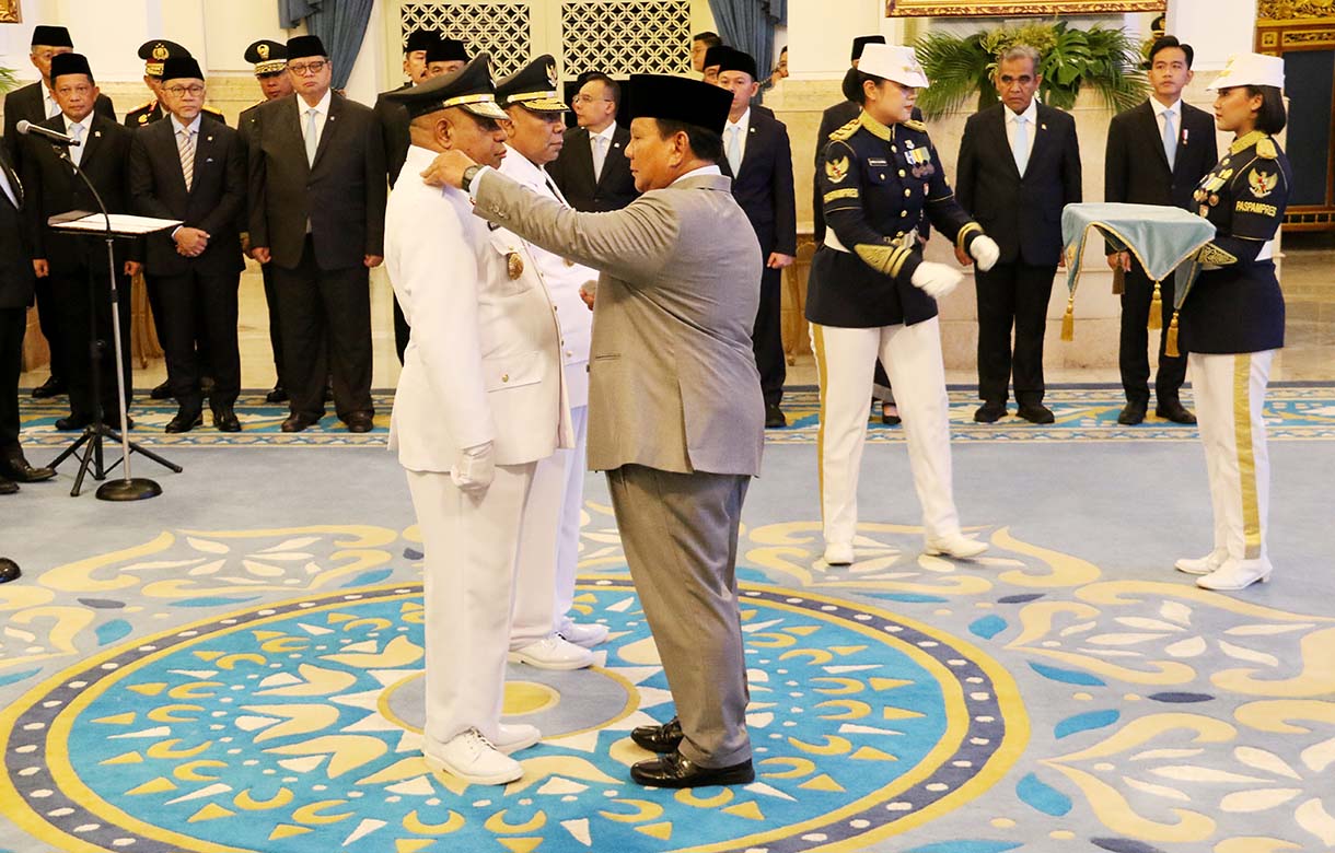 Presiden Prabowo Subianto (kanan) memasang tanda jabatan kepada Gubernur Papua Mathius Fakhiri (kiri) disaksikaan Wakil Gubernur Aryoko Rumaropen (dua kiri). (Beritanasional/Oke Atmaja)