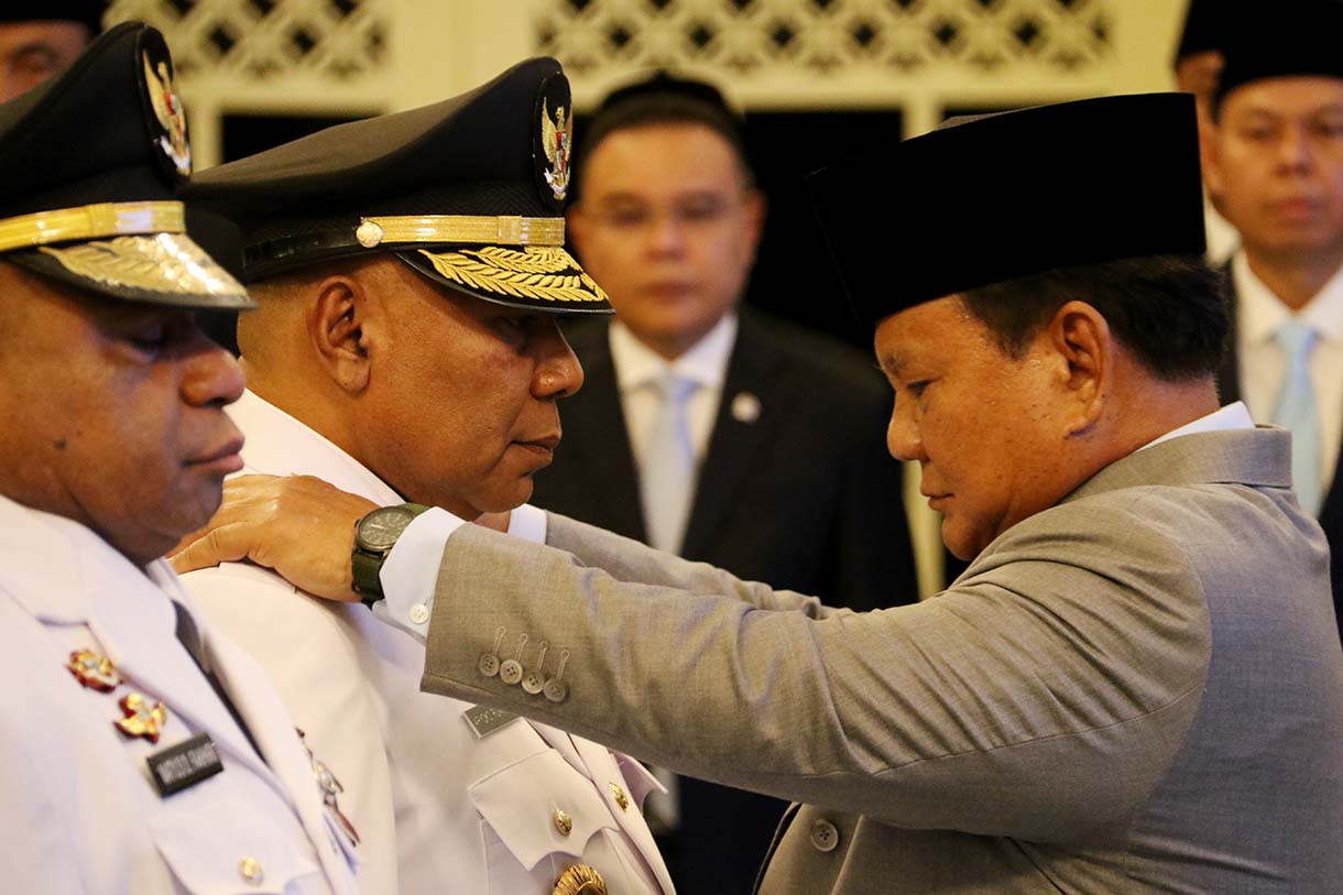 Presiden Prabowo Subianto (kanan) memasang tanda jabatan kepada Gubernur Papua Mathius Fakhiri (kiri) disaksikaan Wakil Gubernur Aryoko Rumaropen (kedua kiri) saat acara pelantikan di Istana Negara, Jakarta, Rabu (8/10/2025).  (Beritanasional.com/Oke Atmaja)