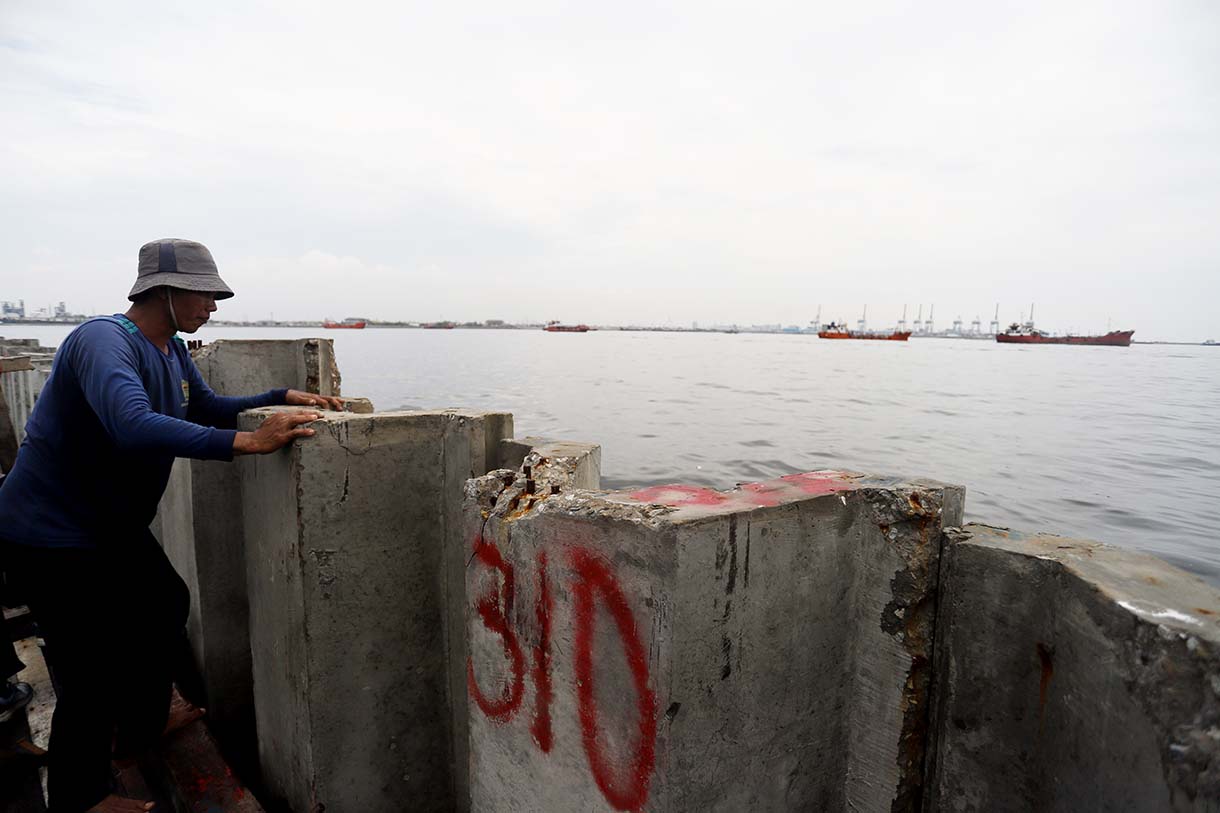 Nelayan berada di atas proyek tanggul beton di perairan Cilincing, Jakarta, Minggu(14/9/2025).  (Beritanasional.com/Oke Atmaja)