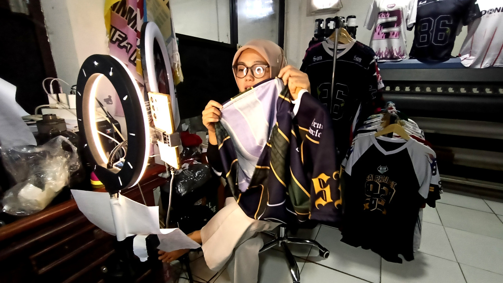 Pekerja menawarkan produk melalui siaran langsung menggunakan platform perdagangan elektronik (e-commerce) di  Industri Konveksi Rumahan Sinergi Adv Nusantara, Jagakarsa, Jakarta Selatan, Rabu (6/8/2025). (Beritanasional.com/Oke Atmaja)