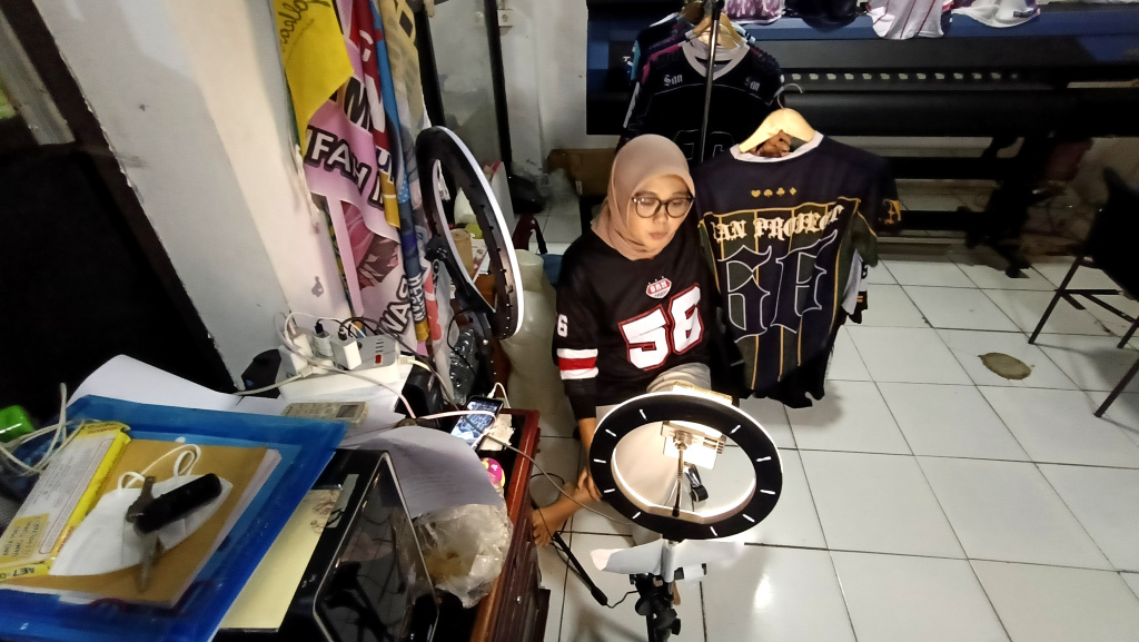 Pekerja menawarkan produk melalui siaran langsung menggunakan platform perdagangan elektronik (e-commerce) di  Industri Konveksi Rumahan Sinergi Adv Nusantara, Jagakarsa, Jakarta Selatan, Rabu (6/8/2025). (Beritanasional.com/Oke Atmaja)