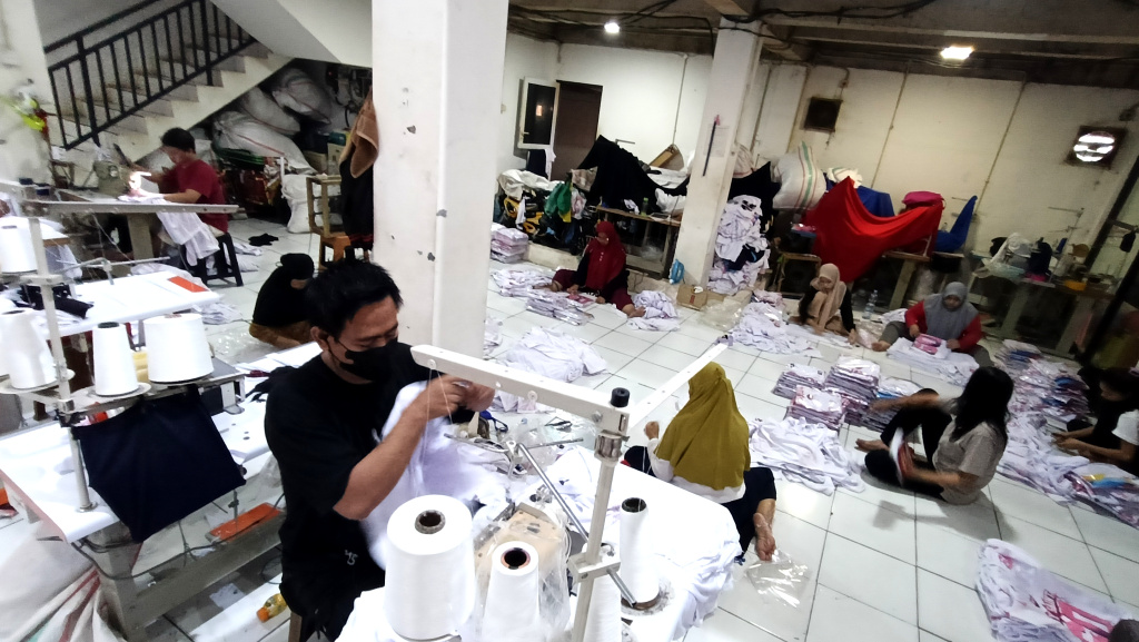 Pekerja menjahit pakaian di bengkel kerja Sinergi Adv di kawasan Srengseng Sawah, Jakarta Selatan, Kamis (16/7/2025).  (Beritanasional.com/Oke Atmaja)