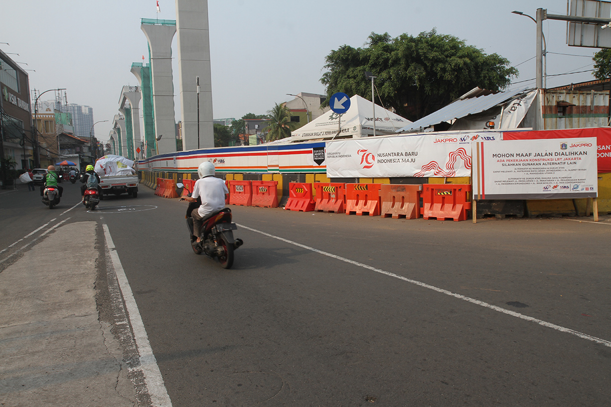 Warga melintas di depan papan informasi pengalihan arus lalu lintas akibat proyek pembangunan jalur kereta ringan atau Lintas Rel Terpadu (LRT) Jakarta Fase 1B rute Velodrome-Manggarai di Jalan Tambak, Jakarta, Minggu (15/9/2024).  (BeritaNasional.com/ Oke Atmaja)