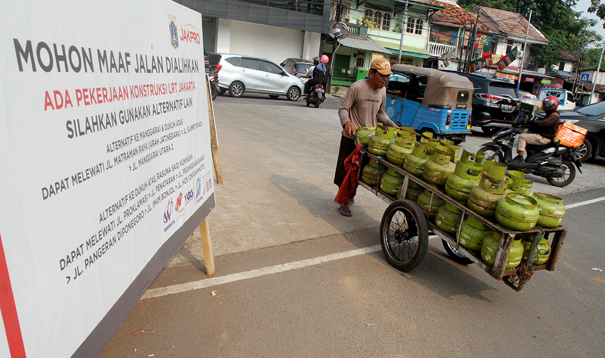 Warga melintas di depan papan informasi pengalihan arus lalu lintas akibat proyek pembangunan jalur kereta ringan atau Lintas Rel Terpadu (LRT) Jakarta Fase 1B rute Velodrome-Manggarai di Jalan Tambak, Jakarta, Minggu (15/9/2024).  (BeritaNasional.com/ Oke Atmaja)