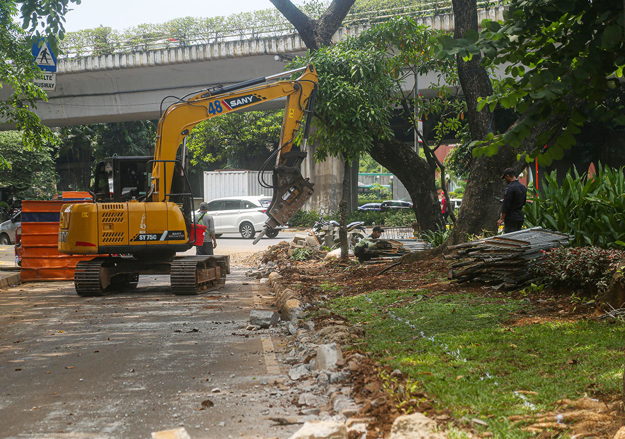 Pekerja menggunakan alat berat menyelesaikan perbaikan trotoar di Jalan Prof. DR. Soepomo, Jakarta, Rabu (9/10/2024).(BeritaNasional.com/Oke Atmaja)