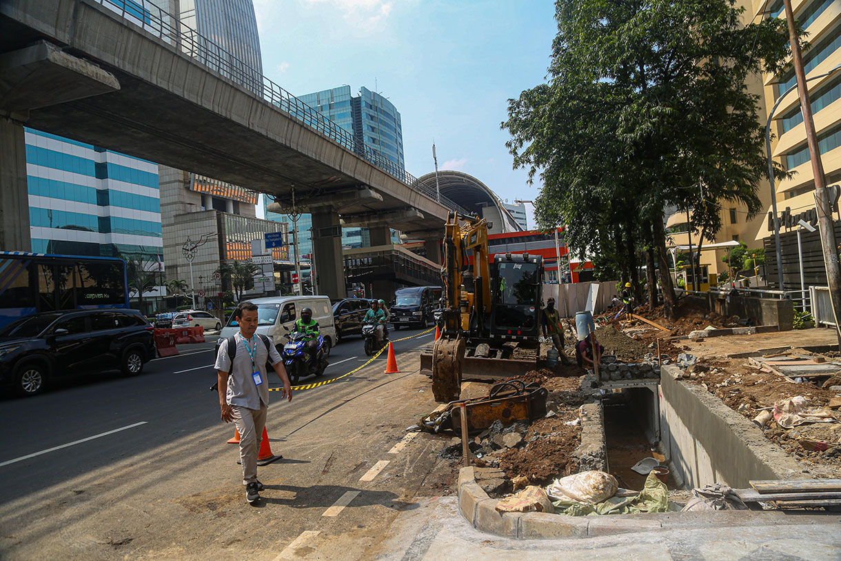 Pejalan kaki melintasi proyek revitalisasi trotoar di Jalan Rasuna Said, Kuningan, Jakarta, Selasa (8/10/2024).(BeritaNasional.com/Oke Atmaja)