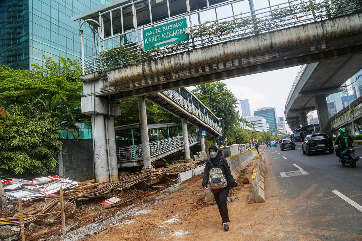 Pejalan kaki melintasi proyek revitalisasi trotoar di Jalan Rasuna Said, Kuningan, Jakarta, Selasa (8/10/2024).(BeritaNasional.com/Oke Atmaja)