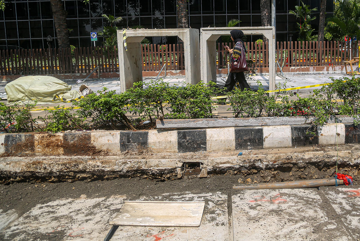 Pejalan kaki melintasi proyek revitalisasi trotoar di Jalan Rasuna Said, Kuningan, Jakarta, Selasa (8/10/2024).(BeritaNasional.com/Oke Atmaja)