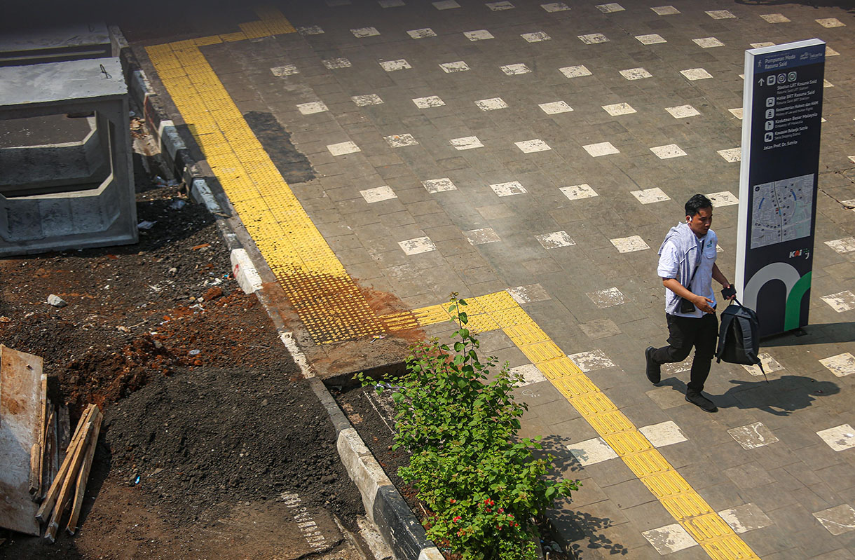 Pejalan kaki melintasi proyek revitalisasi trotoar di Jalan Rasuna Said, Kuningan, Jakarta, Selasa (8/10/2024).(BeritaNasional.com/Oke Atmaja)