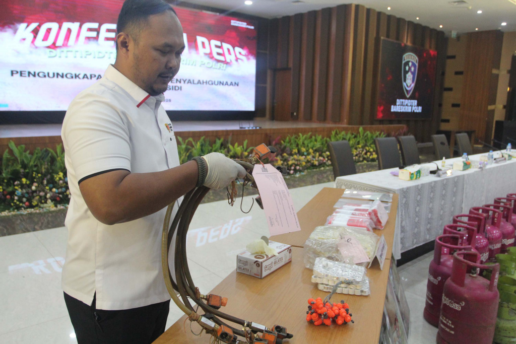 Rilis Kasus Penyuntikan Gas LPG Bersubsidi Petugas menata barang bukti tabung gas LPG 3 kilogram bersubsidi pada keterangan pers terkait kasus pengoplosan atau penyuntikan gas LPG bersubsidi di Bareskrim Polri, Jakarta, Senin (5/5/2025). (Beritanasional.com/Oke Atmaja)