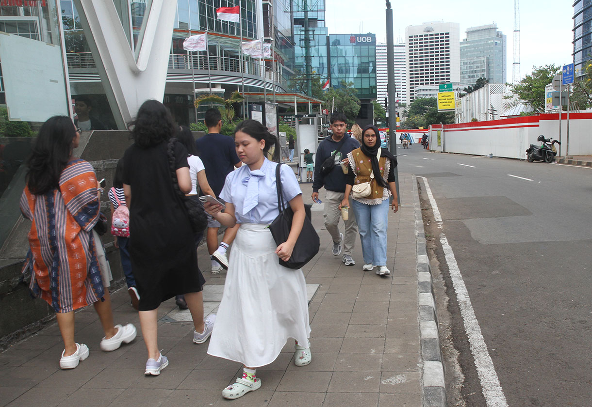 Pejalan kaki berjalan di trotoar Jalan Sudirman, Jakarta, Minggu(29/9/2024). (BeritaNasional.com/Oke Atmaja)