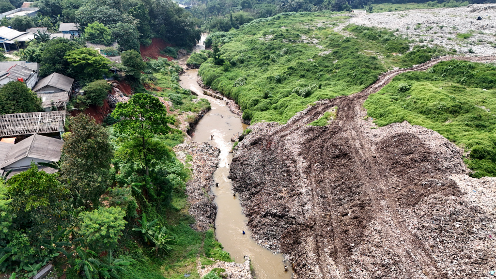 Pemulung menyeberangi Kali Pesanggrahan sambil membawa sampah untuk didaur ulang di Tempat Pembuangan Akhir Cipayung, Depok, Jawa Barat, Kamis (9/5/2024).  (BeritaNasional.com/Oke Atmaja)