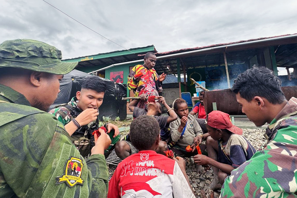 Prajurit Satgas Yonif 509 Kostrad bersama anak-anak Papua berbagi bahagia saat mencoba makan buah merah Papua. (BeritaNasional/HO/Elvis Sendouw)