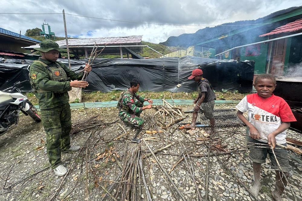 Prajurit Satgas Yonif 509 Kostrad bersama anak-anak Papua berbagi bahagia saat mencoba makan buah merah Papua. (BeritaNasional/HO/Elvis Sendouw)