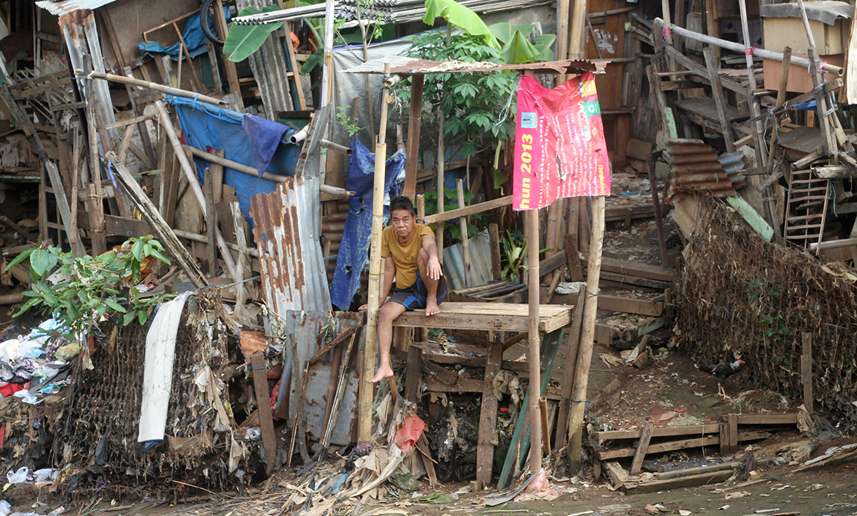 Warga duduk di permukiman bantaran sungai di kawasan Manggarai, Jakarta, Kamis (9/1/2025). (BeritaNasional.com/ Oke Atmaja)