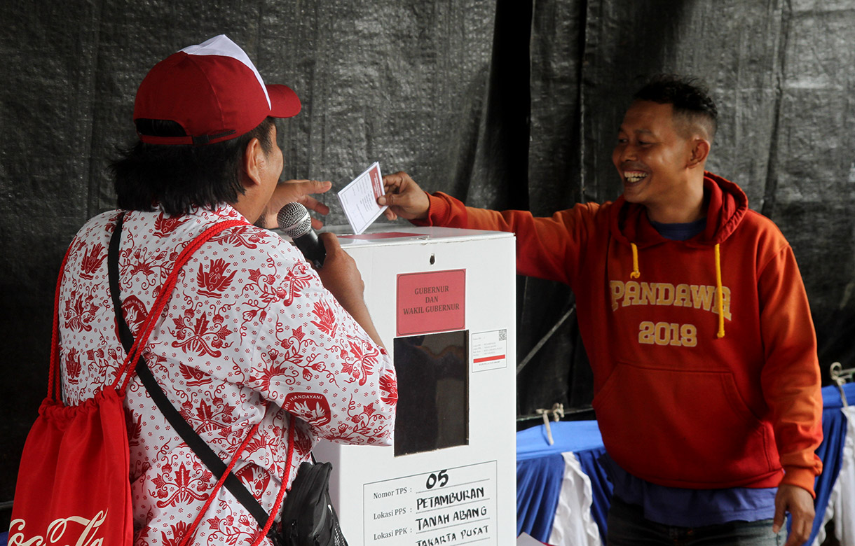 Petugas Kelompok Penyelenggara Pemungutan Suara (KPPS) mengenakan seragam sekolah mengarahkan warga memasukkan surat suara di TPS 05 Petamburan, Tanah Abang, Jakarta, Rabu (27/11/2024).(BeritaNasional.com/Oke Atmaja)