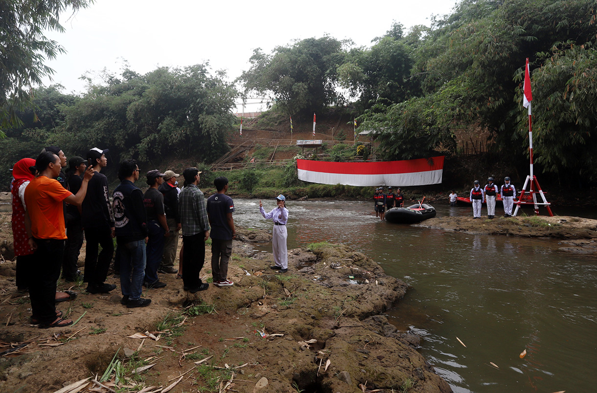 Sejumlah anggota Komunitas Ciliwung mengibarkan bendera Merah Putih saat mengikuti upacara bendera di Sungai Ciliwung, Depok, Jawa Barat, Sabtu, (17/8/2024). (BeritaNasional.com/ Oke Atmaja)