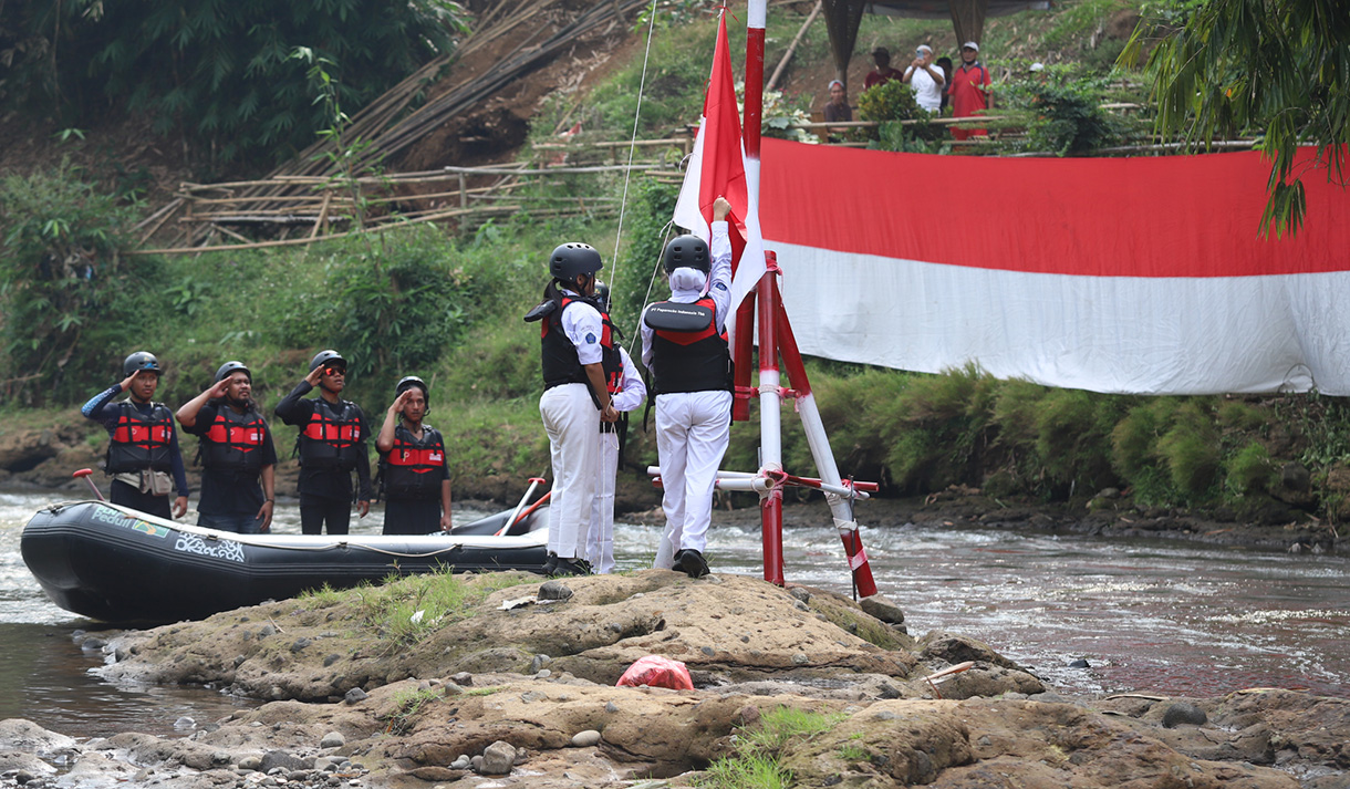 Sejumlah anggota Komunitas Ciliwung mengibarkan bendera Merah Putih saat mengikuti upacara bendera di Sungai Ciliwung, Depok, Jawa Barat, Sabtu, (17/8/2024). (BeritaNasional.com/ Oke Atmaja)