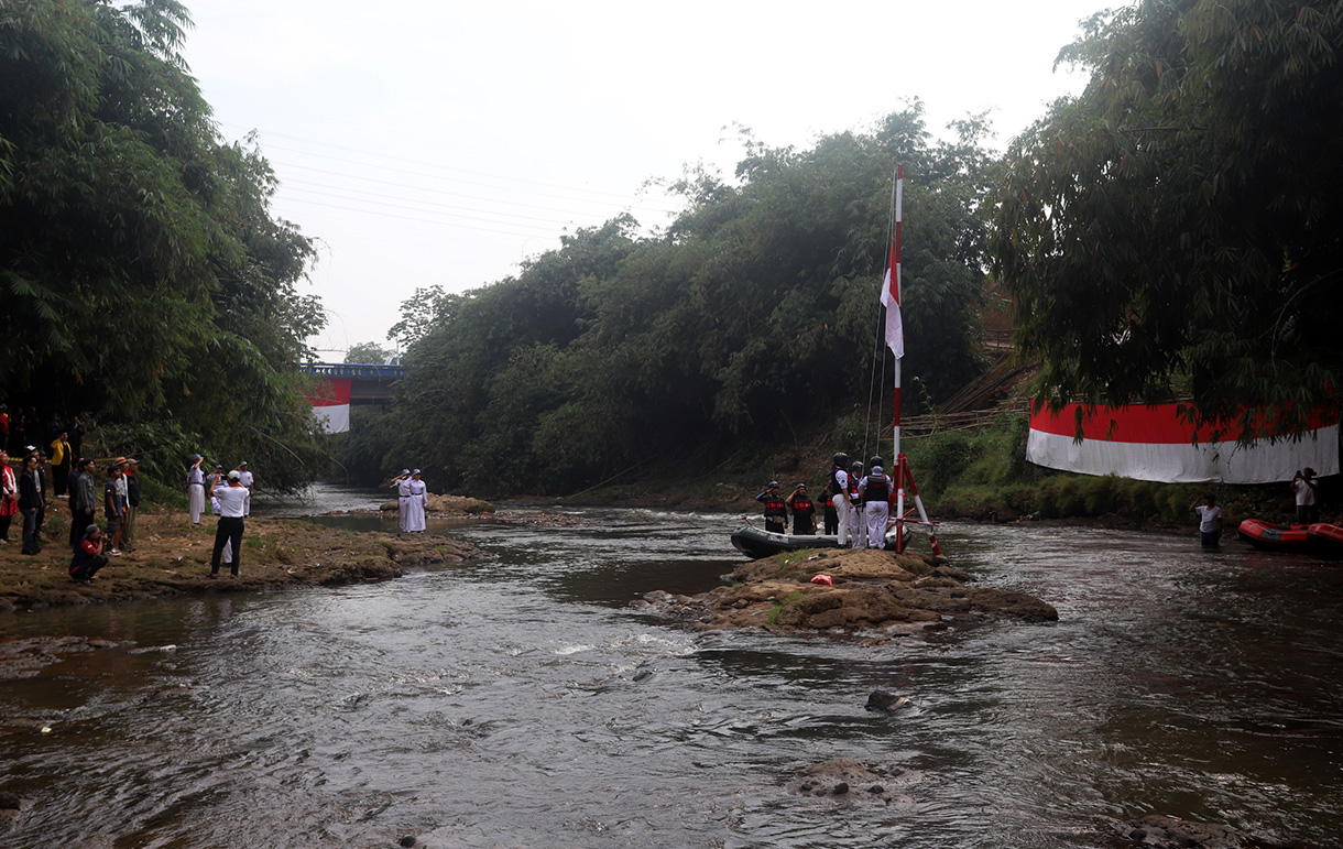 Sejumlah anggota Komunitas Ciliwung mengibarkan bendera Merah Putih saat mengikuti upacara bendera di Sungai Ciliwung, Depok, Jawa Barat, Sabtu, (17/8/2024). (BeritaNasional.com/ Oke Atmaja)