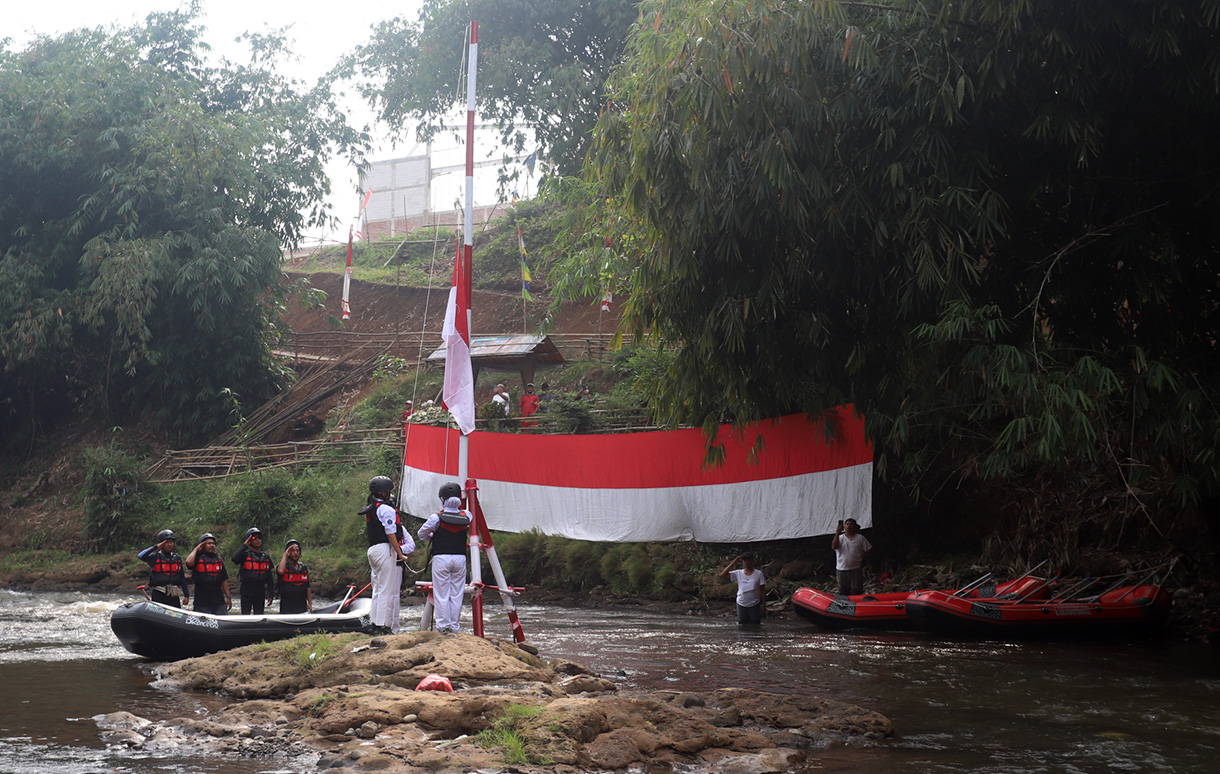 Sejumlah anggota Komunitas Ciliwung mengibarkan bendera Merah Putih saat mengikuti upacara bendera di Sungai Ciliwung, Depok, Jawa Barat, Sabtu, (17/8/2024). (BeritaNasional.com/ Oke Atmaja)