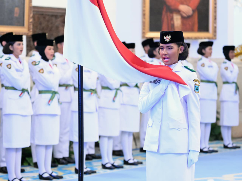 Anggota Paskibraka 2025 asal Papua Barat Ritha Lovely CF Ayomi mencium Bendera Merah-Putih dalam upacara pengukuhan Paskibraka Tingkat Pusat 2025 di Istana Negara, Jakarta, Sabtu (16/8/2025).  (Beritanasional.com/ Biro Pers)